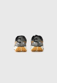 Black and gray patterned athletic shoes with a textured finish, featuring orange accents and a rugged, rubber outsole with traction grooves.