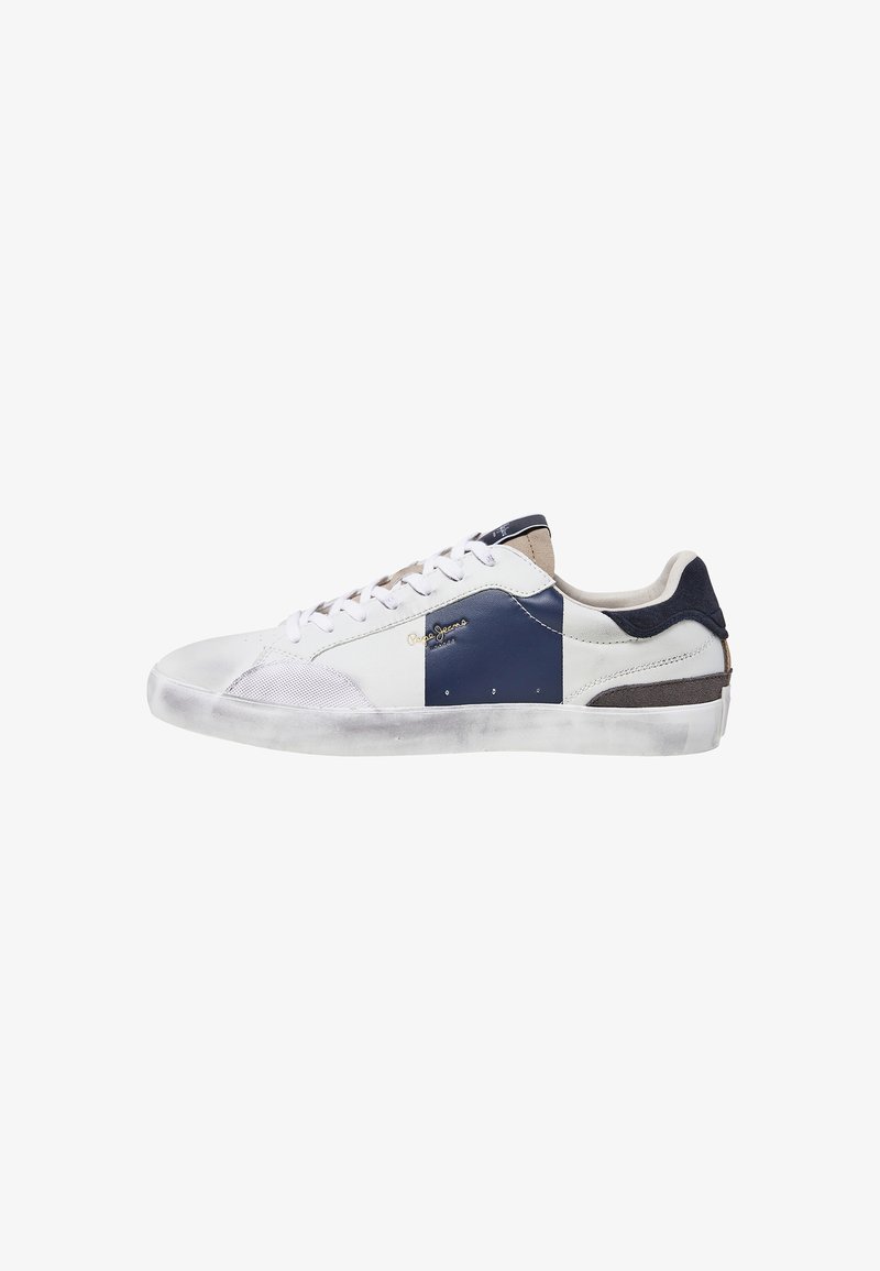 Zapatilla blanca con acentos en azul marino y marrón, con un diseño de cuero y malla, punta redondeada, suela de goma plana y costuras decorativas.