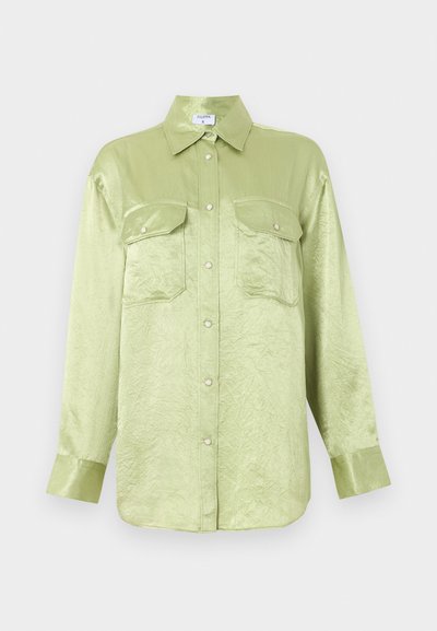 Φωτεινό πράσινο σατέν πουκάμισο με μακριά μανίκια, μπροστινά κουμπώματα με τρουκς, δύο πιέτες στο στήθος με κουμπιά και μυτερό γιακά.