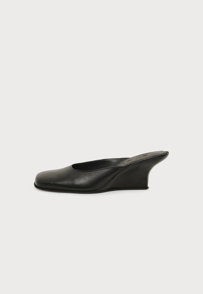 Mule à talon pour femme en cuir noir avec bout carré et talon compensé incurvé sur fond uni.