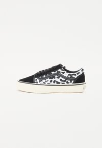 Sorte og hvite joggesko med leopardmønster, laget av semsket skinn og lerret, lavt design og hvit gummisål.