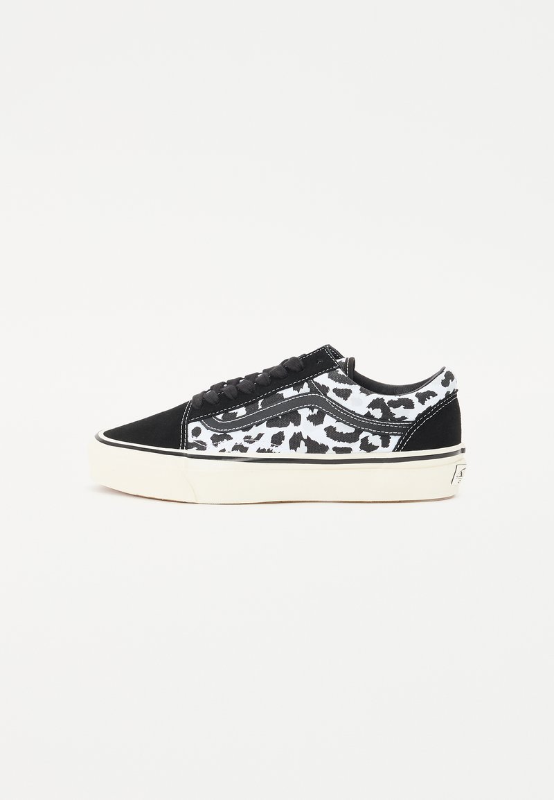 Sorte og hvite joggesko med leopardmønster, laget av semsket skinn og lerret, lavt design og hvit gummisål.