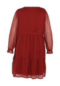 Robe rouge avec de longues manches transparentes, jupe à volants et petit motif floral blanc sur l'ensemble. Présente des poignets froncés et un col rond.