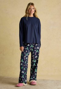 Tumedast riidest pikad varrukad ja mustriga püksid, millel on puid ja talveüritusi; pehmed roosad sussid, millel on karvased detailid.