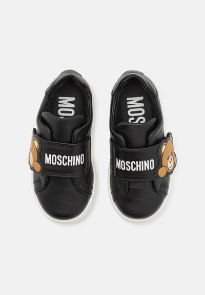 Sneaker nere in pelle con suola bianca, dotate di una fascia in Velcro con un design di orso bruno e il marchio "MOSCHINO" in bianco.