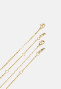 Gold-tone layered chains with varying textures, circular links, and lobster clasps. Features engraved brand tags on two chains.