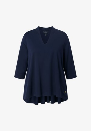 Námořnický modrý top se třičtvrtinovými rukávy a výstřihem do V. Měkká látka a rozšířený asymetrický lem. Obsahuje malý zlatý akcent loga.