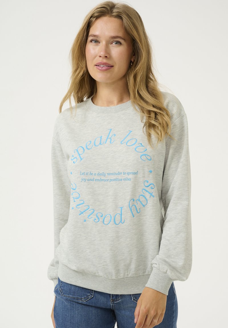 Hellgrauer Hoodie aus weichem Stoff mit blauen Text in kreisförmigem Muster. Das Design umfasst einen Rundhalsausschnitt und gerippte Bündchen.
