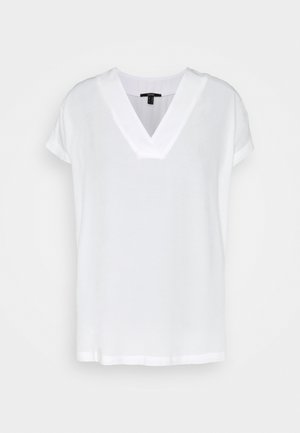 Biała bluzka z krótkim rękawem i dekoltem w serek, o lekko luźnym kroju, przedstawiona na jednolitym białym tle.