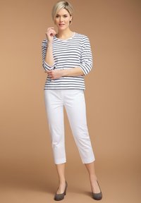 Gestreepte lange mouwtop in het wit met marineblauwe lijnen, gecombineerd met witte cropped broeken en grijze hoge hakken. Glad materiaal en een ontspannen pasvorm.