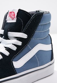 Baskets montantes avec une tige en tissu noir et bleu, des accents blancs, des lacets ronds et une étiquette logo Vans à la cheville. Semelle blanche.