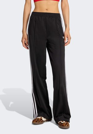 Czarne spodnie sportowe z białymi bocznymi paskami, wykonane z gładkiej tkaniny, z elastycznym pasem i dwoma przednimi kieszeniami na zamek.