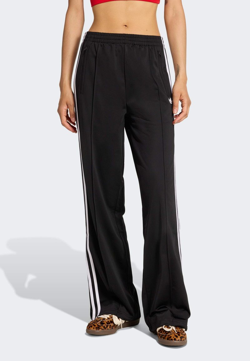 Czarne spodnie sportowe z białymi bocznymi paskami, wykonane z gładkiej tkaniny, z elastycznym pasem i dwoma przednimi kieszeniami na zamek.