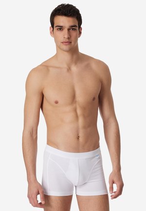 White cotton boxer briefs with a snug fit, featuring a soft waistband and a front pouch, displayed on a standing male model.
