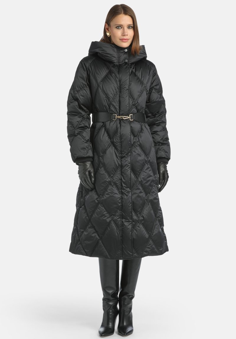 Palton lung puf cu quiltat negru, cu glugă, talie încinsă și cusături diagonale. Purtați cu mănuși negre și cizme până la genunchi. Finisaj lucios.