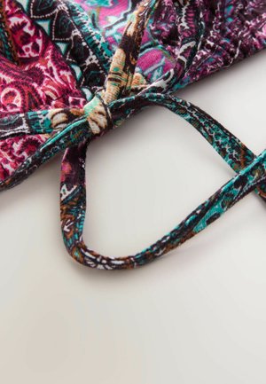 Bunt gefärbtes Stoffband mit ausgefallenen Mustern in Pink, Türkis und Braun, zu einem Knoten gebunden. Die Textur wirkt weich und dehnbar.