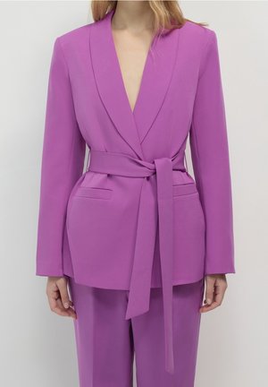 Paarse blazer met een diepe V-hals, lange mouwen, voorzakken en een tailleband. Gemaakt van gladde stof met een getailleerde pasvorm.