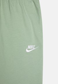 Zelené bavlněné šortky s bílou vyšívanou logem Nike. Elastický pas a měkká textura s jednoduchým designem.