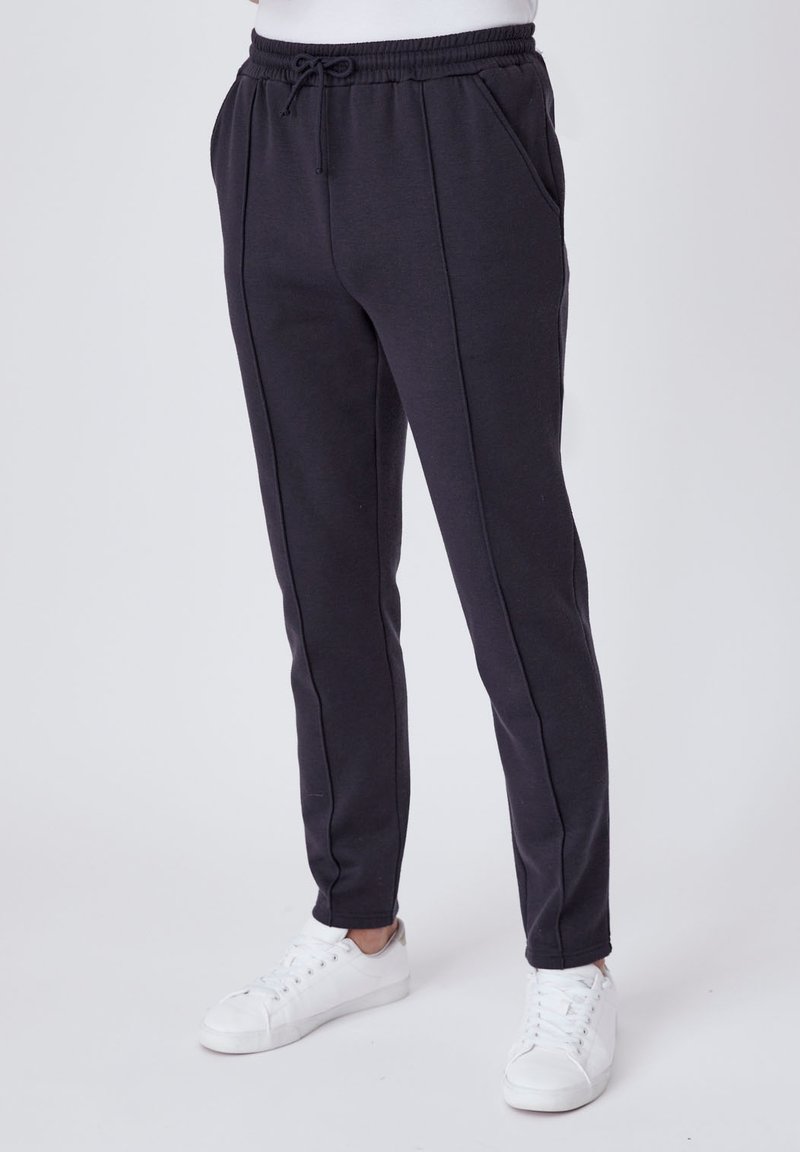 Zwarte sweatpants met een elastische tailleband en trekkoord, voorzien van schuine zijzakken en een slanke pasvorm, gemaakt van zachte stof.