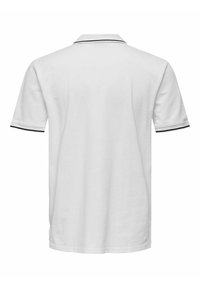 Camiseta polo blanca de algodón, con un cuello clásico con ribete negro y mangas cortas con acentos negros a juego.
