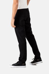 Jeans de mezclilla negra con corte recto, que presentan bolsillos traseros y una textura suave. Llevados con zapatillas negras y una camisa blanca ajustada.