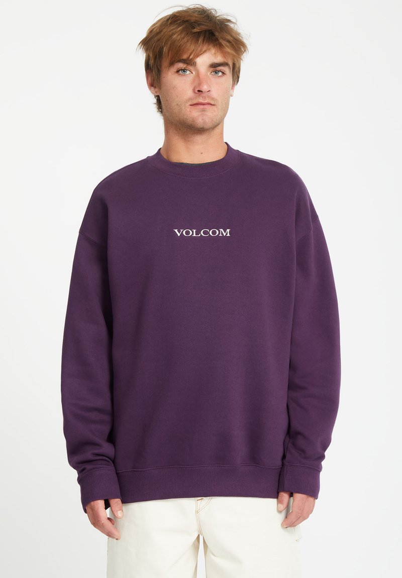 Sweatshirt violet à manches longues et col ras du cou, arborant le logo "VOLCOM" en blanc. Fabriqué en tissu doux avec une coupe décontractée.