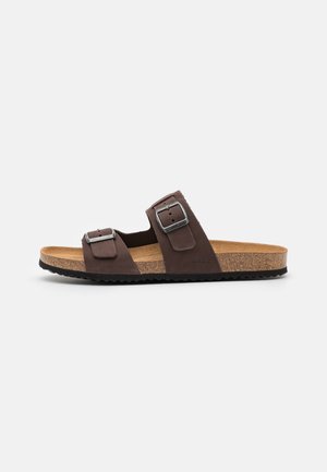 Brown two-strap sandals with adjustable metal buckles, cork footbed, and rubber sole. Features smooth texture and a casual design.