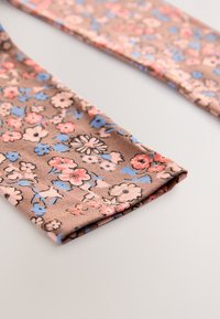Blomstret stof med beige baggrund og rosa samt blå blomster. Blød tekstur med let strækbart materiale, synlige foldede kanter.