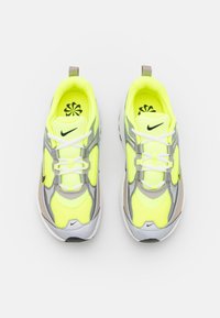 Footwear featuring bright yellow mesh upper with gray and beige accents, white laces, and a distinctive logo. Thick rubber sole.