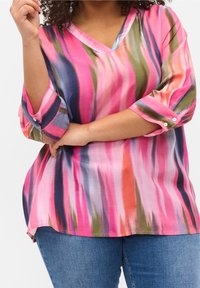 Blouse à encolure en V et manches trois-quarts avec un motif tourbillonnant multicolore en rose, bleu, vert et orange. Tissu lisse et léger.