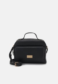 Sac à main en cuir noir avec fermeture éclair, doté d'une poche avant, d'une surface texturée, de ferrures dorées et d'une bandoulière amovible.