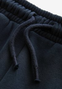 Navyblaue Sweatpants mit einer weichen Textur, ausgestattet mit einem elastischen Bund und verstellbaren Kordeln mit geflochtenen Details.
