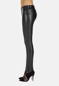 Czarne legginsy z ekologicznej skóry o dopasowanym kroju, wysokim stanie, bocznych kieszeniach i pionowych szwach, zestawione z czarnymi butami na wysokim obcasie.