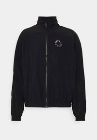 Chaqueta negra con un cuello alto y cierre de cremallera. Presenta puños y cintura elásticos. En la parte delantera hay texto blanco y un diseño de logo circular.