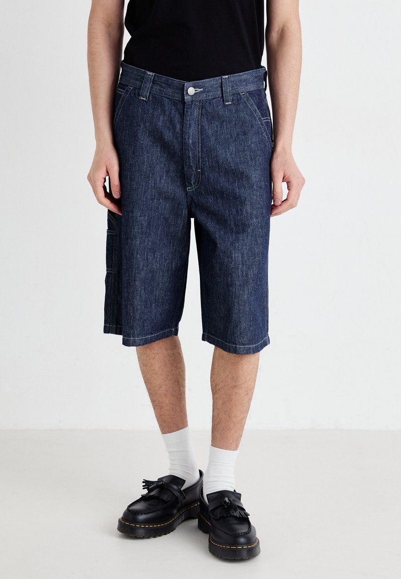 Denim shorts in dark blue, featuring a straight cut, front pockets, and a side cargo pocket, finished with contrasting stitching.