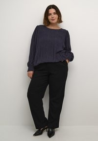 Top morado oscuro con rayas plateadas verticales, escote redondo y mangas tipo globo, combinado con pantalones negros y tacones negros de punta.