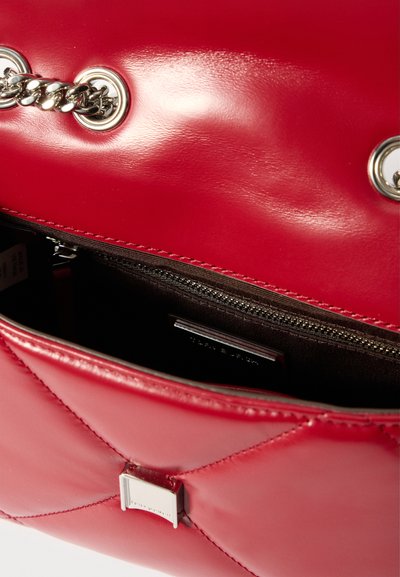 Κόκκινη επενδεδυμένη δερμάτινη τσάντα με ασημί αλυσίδα, μισάνοιχτη δείχνοντάς μας τη σκοτεινή θήκη με φερμουάρ μέσα.