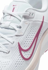 Scarpa sportiva bianca con tomaia texturizzata, logo swoosh Nike rosa e lacci bianchi. Presenta una suola morbida e ammortizzata con il marchio ComfiRide.