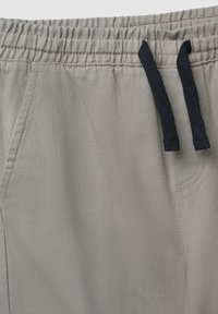 Jasnoszare spodnie z teksturowanej tkaniny, z elastycznym pasem i czarnymi sznureczkami oraz detalem bocznej kieszeni.