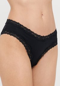 Mutande nere con pizzo lungo l'elastico in vita e le aperture delle gambe, realizzate in un tessuto morbido ed elasticizzato per un comfort ottimale.