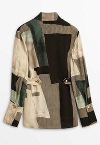 Veste à motifs multiples présentant des formes vertes, beiges et noires avec des rayures verticales. Manches longues avec des boutons décoratifs et un col ajusté.