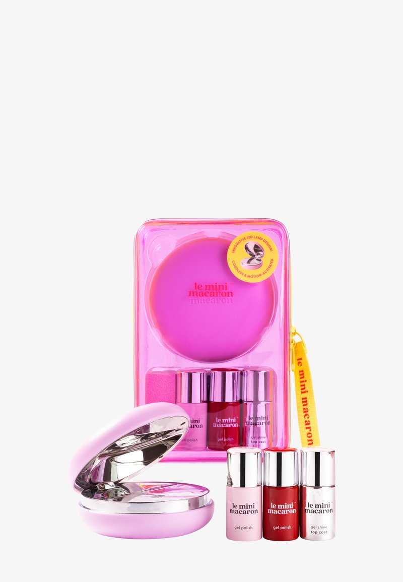 Portable pink LED nail lamp with three bottles of le mini macaron gel polish and a yellow branded zipper pouch.