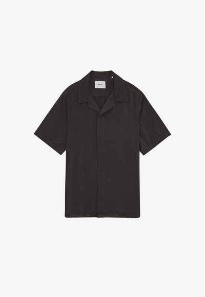 Chemise noire à manches courtes avec boutons, col camp et boutons cachés, avec une étiquette blanche à l’intérieur de l’encolure.