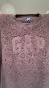 Sweat-shirt texturé marron de GAP avec un symbole de cœur à l'intérieur de la lettre A, tenu par les mains aux coins supérieurs