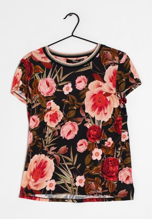 Camisa negra de manga corta con estampado floral en rosa, rojo y durazno colgando de una percha negra sobre un fondo blanco.