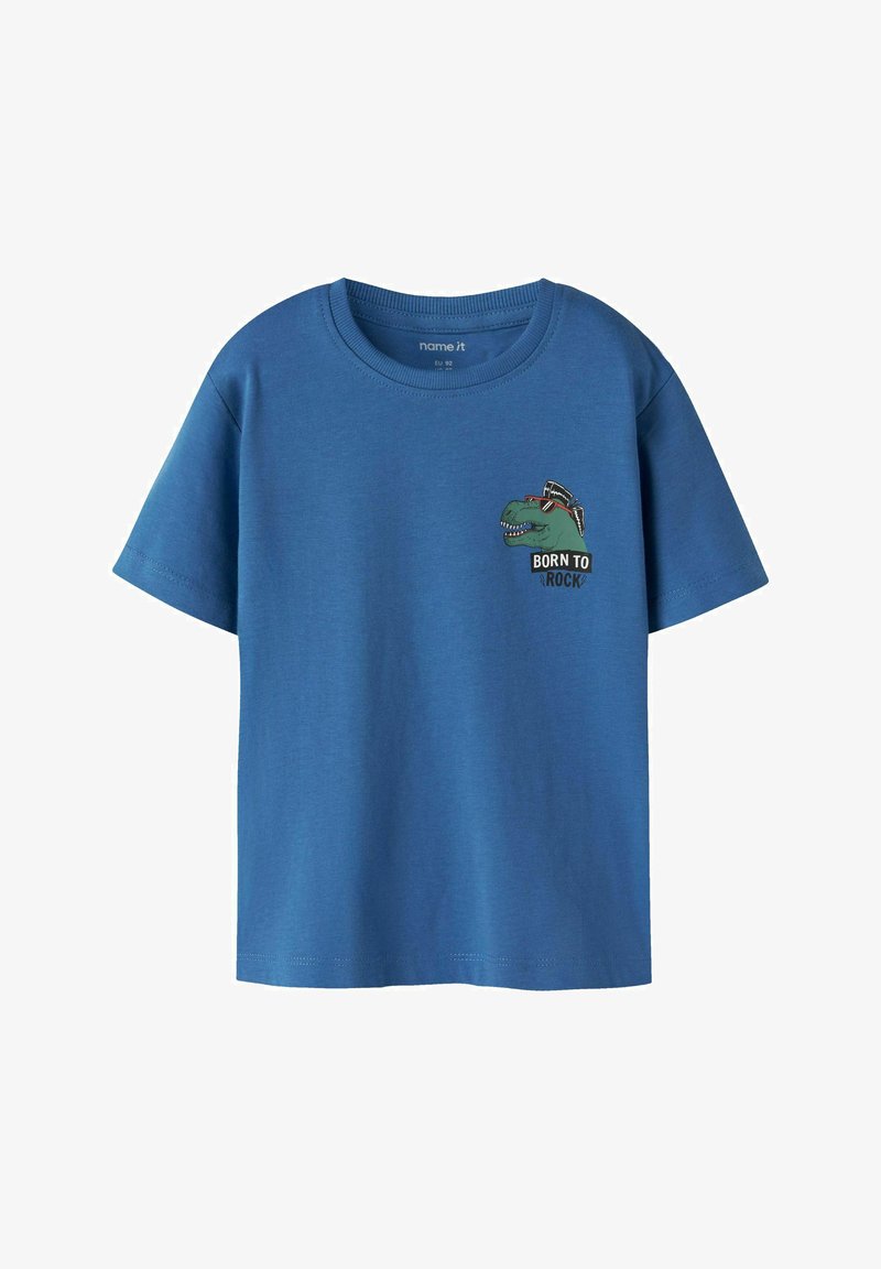 Camiseta azul de manga corta con un pequeño dinosaurio verde que lleva gafas de sol y cresta, texto "BORN TO ROCK" en el pecho delantero izquierdo.