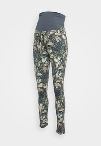 Těhotenské legíny s tmavě modrým páskem. Tkanina má listový vzor v zelených a béžových tónech na tmavém pozadí.