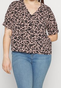 Blouse à manches courtes et col en V, rose avec un imprimé léopard noir. Boutons sur le devant, coupe décontractée et texture de tissu douce.