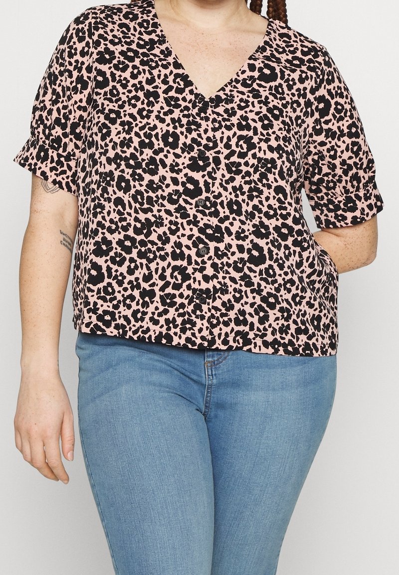 Blouse à manches courtes et col en V, rose avec un imprimé léopard noir. Boutons sur le devant, coupe décontractée et texture de tissu douce.