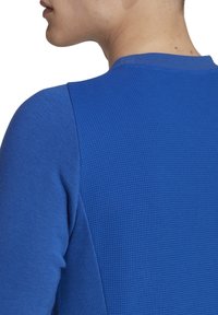 Blauwe gestructureerde lange mouwen shirt met een soepel gebreid lichaam en een patroonaccent op de schouder, ronde halslijn.